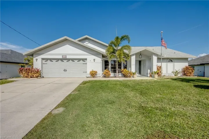 Front exterior of this well-maintained Cape Coral home with mature landscaping and wide driveway.