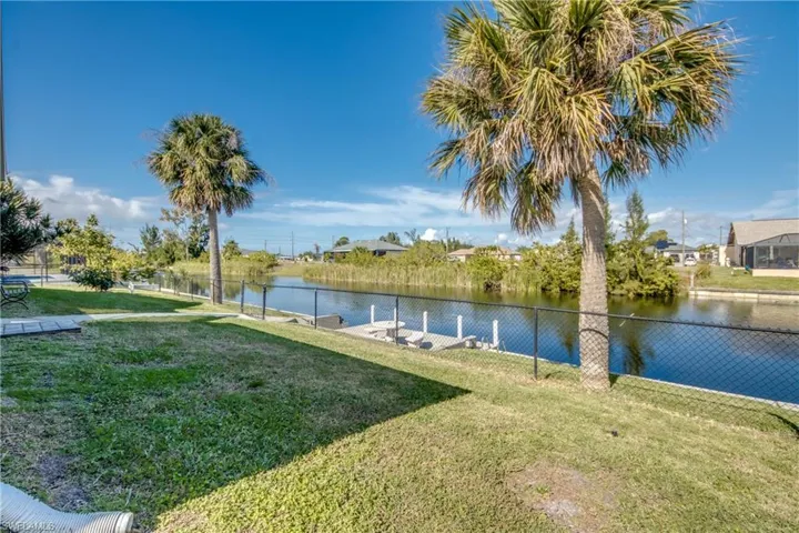 Fenced backyard with grassy area and canal frontage—great outdoor space in Cape Coral, FL.