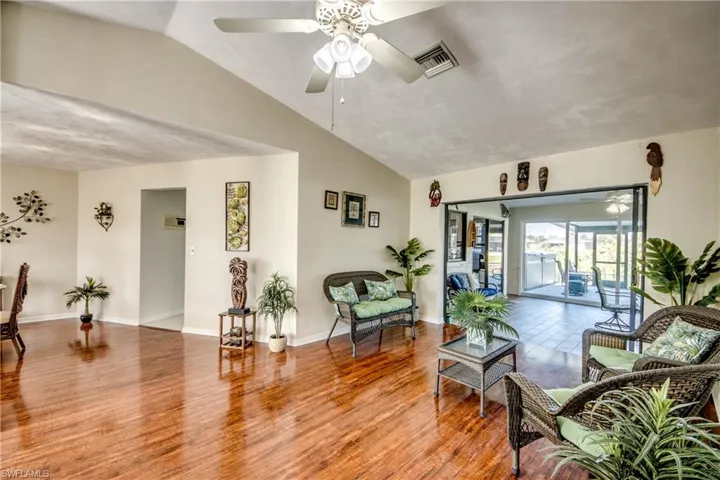 Sitting room with vaulted ceiling, wood-finished floors, and flexible living space.