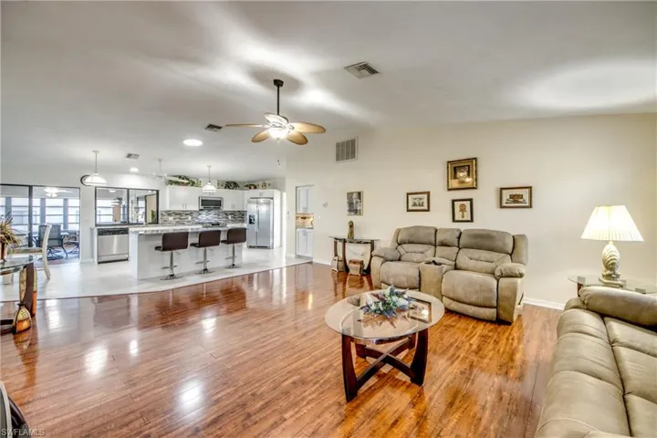 Living area featuring light wood finished floors, vaulted ceiling, ceiling fan, and recessed lighting
