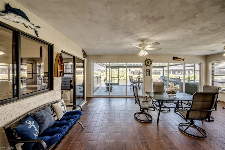 Sunroom with expansive windows and wood-finished floors overlooking the freshwater canal.