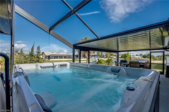 Swim spa under the screened enclosure with canal views—a standout feature for Cape Coral Florida buyers.