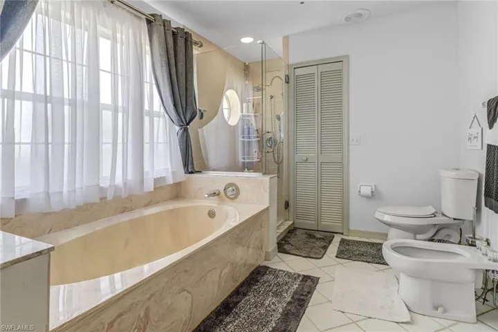 Bathroom featuring a bidet, tile patterned floors, vanity, toilet, and a washtub