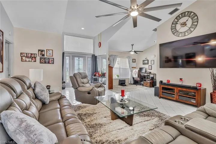 Tiled living room with ceiling fan and high vaulted ceiling