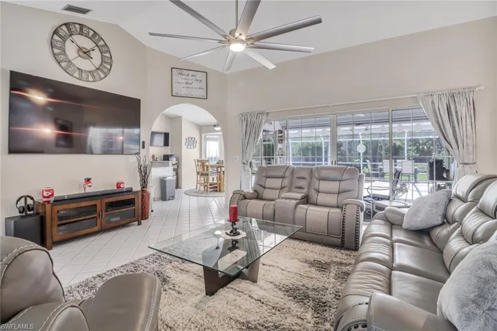 Tiled living room featuring ceiling fan and high vaulted ceiling