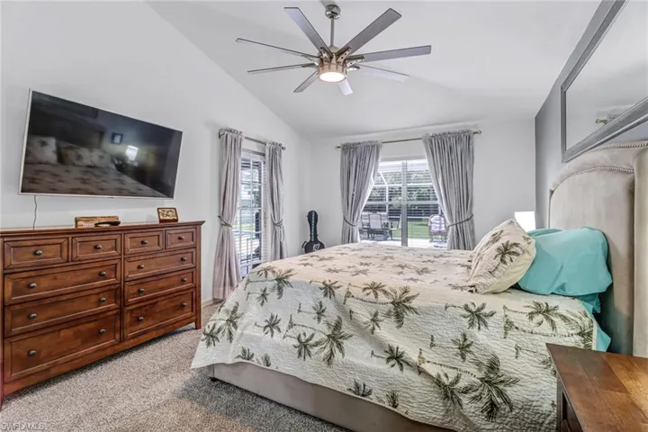 Carpeted bedroom featuring ceiling fan and lofted ceiling