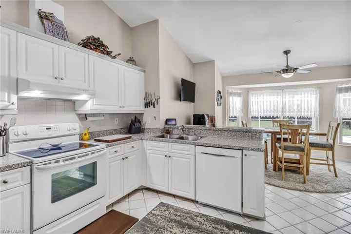 Kitchen featuring white cabinets, a wealth of natural light, sink, and white appliances