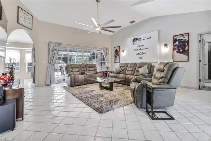 Living room with vaulted ceiling, light tile patterned floors, and ceiling fan