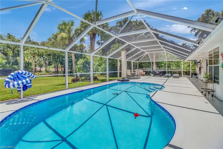 View of pool with glass enclosure, a lawn, and a patio