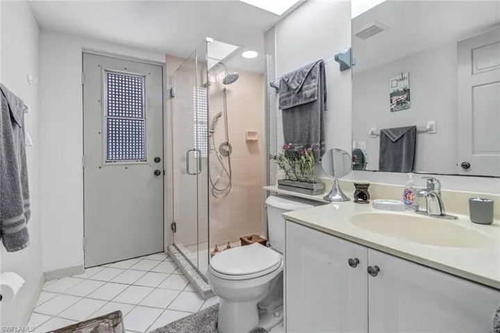 Bathroom with tile patterned flooring, vanity, toilet, and a shower with shower door