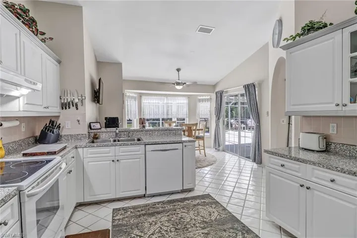 Kitchen featuring tasteful backsplash, white appliances, sink, and white cabinets