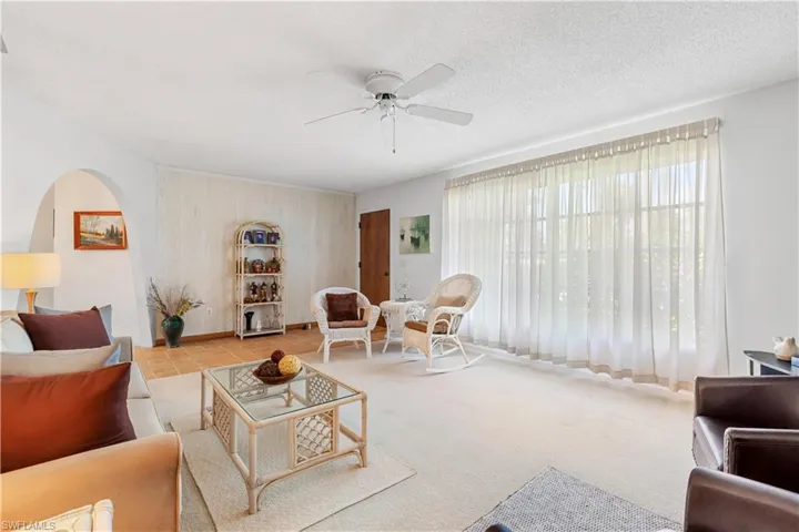 Carpeted living room with a textured ceiling and ceiling fan