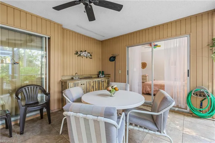Tiled dining space featuring a textured ceiling, wooden walls, and ceiling fan