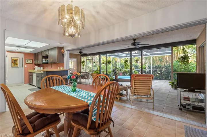 Dining room featuring ceiling fan with notable chandelier, a wealth of natural light, and light tile patterned floors