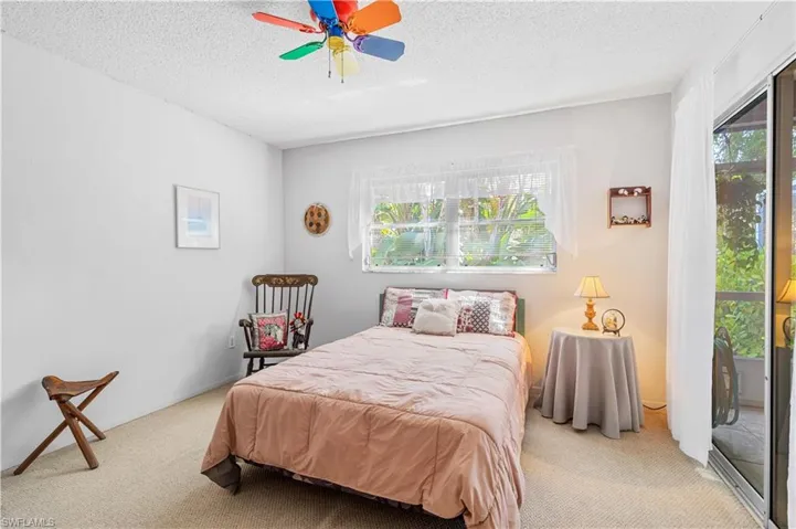 Bedroom featuring light carpet, a textured ceiling, multiple windows, and ceiling fan