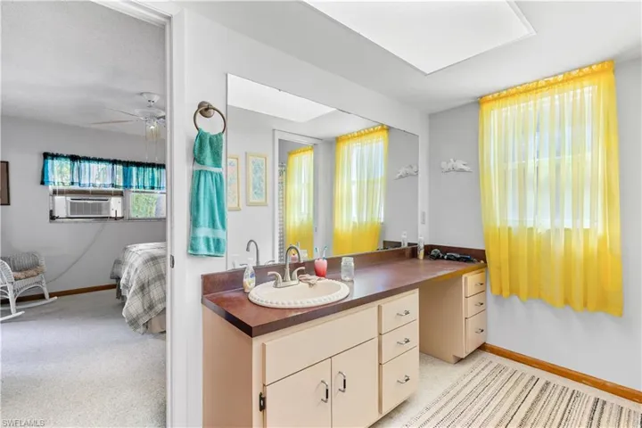 Kitchen featuring cooling unit, sink, ceiling fan, and light colored carpet