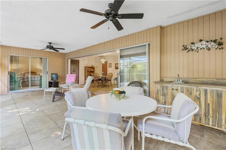 Tiled dining space with wood walls, a textured ceiling, and ceiling fan