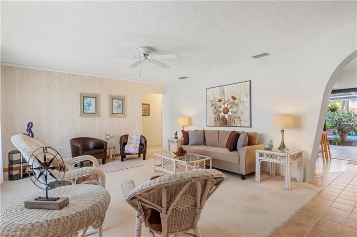 Living room featuring a textured ceiling, ceiling fan, and light tile patterned floors