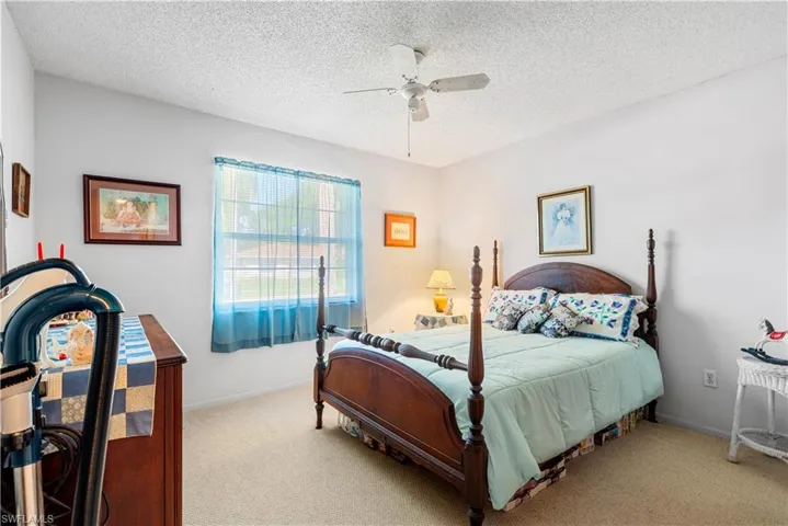 Bedroom with light colored carpet, a textured ceiling, and ceiling fan