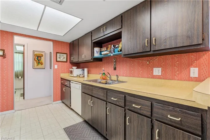 Kitchen featuring light tile patterned floors, dishwasher, sink, and dark brown cabinetry