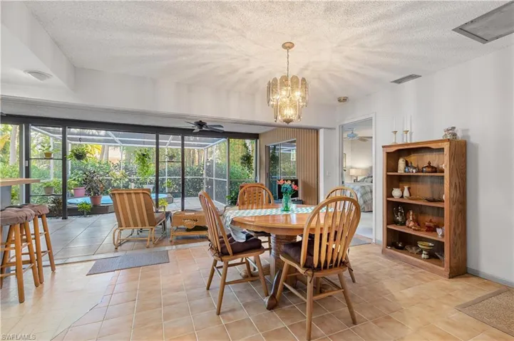 Tiled dining room featuring a textured ceiling and ceiling fan with notable chandelier
