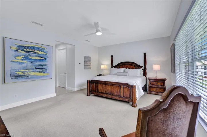 Bedroom with multiple windows, light colored carpet, and a ceiling fan