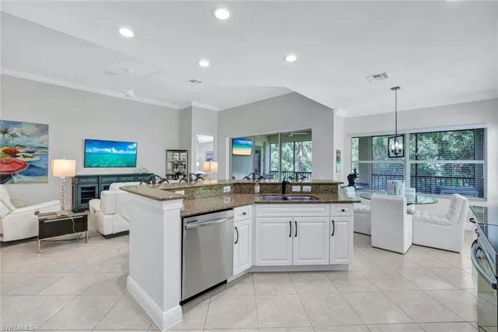 Kitchen with dishwasher, open floor plan, ornamental molding, dark stone countertops, and light tile patterned floors