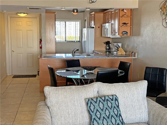 Kitchen with light tile patterned floors, a peninsula, freestanding refrigerator, range, and brown cabinets