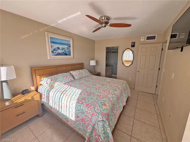 Master Bedroom featuring light tile patterned floors, connected bathroom, and a ceiling fan