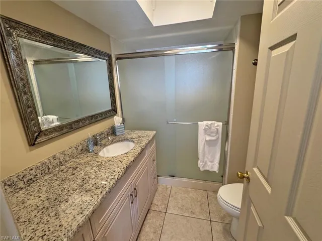 Full Master bath with vanity, light tile patterned flooring, and a shower stall