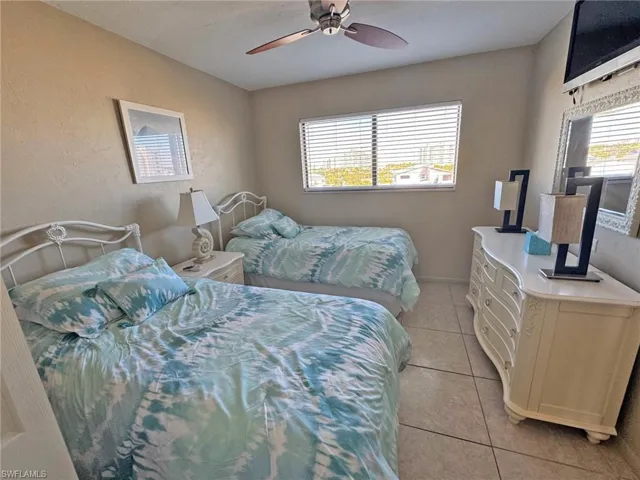 Guest Bedroom featuring light tile patterned floors, a ceiling fan, and a textured wall