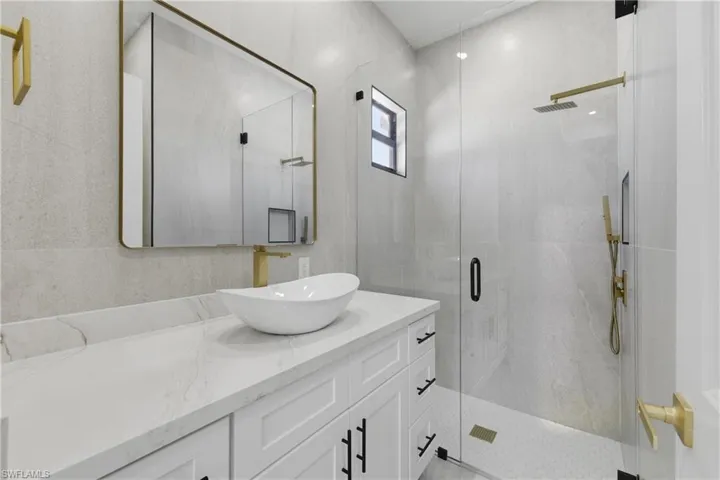 Full bath featuring a stall shower, vanity, and tile walls