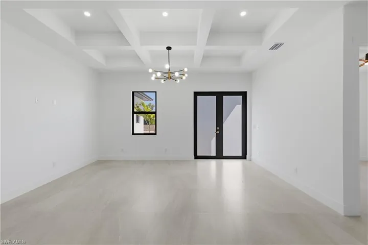 Spare room with a chandelier, coffered ceiling, and french doors