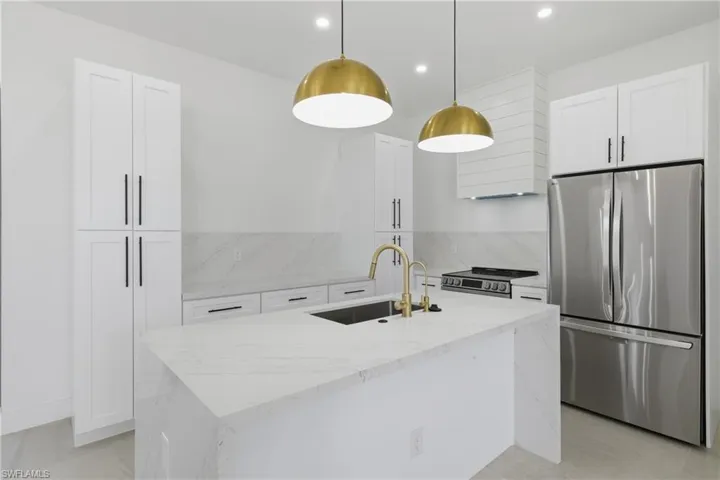 Kitchen with light stone countertops, stainless steel appliances, and white cabinets