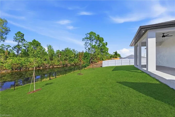 Fenced yard featuring ceiling fan and a water view