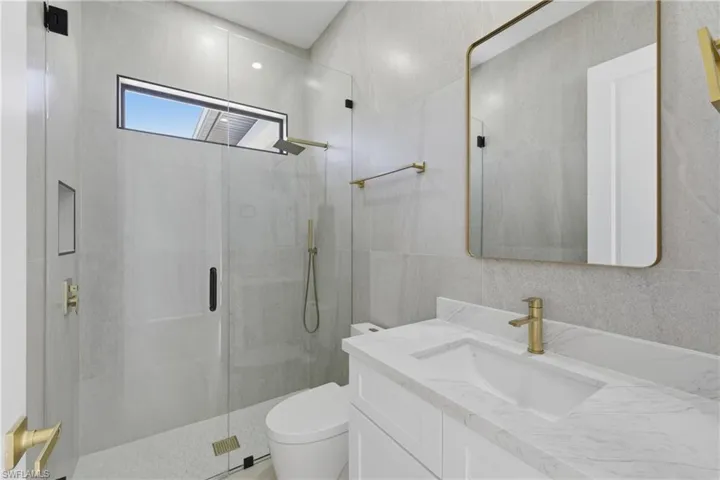 Bathroom featuring a stall shower, vanity, and tile walls