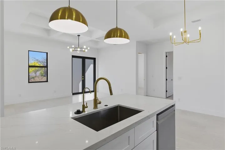 Kitchen with a chandelier, light stone countertops, coffered ceiling, dishwasher, and white cabinetry