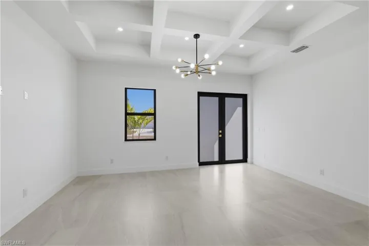 Unfurnished room featuring coffered ceiling, a chandelier, and french doors
