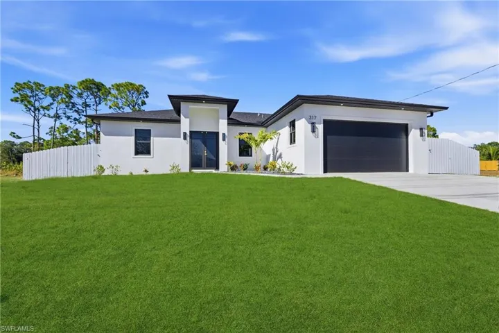 Prairie-style house with a gate, stucco siding, concrete driveway, and a garage