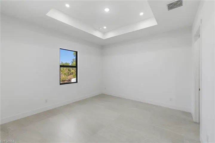 Empty room with recessed lighting and a tray ceiling
