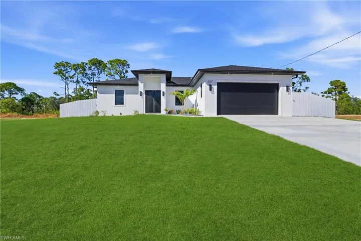 Prairie-style home featuring driveway, stucco siding, and a garage