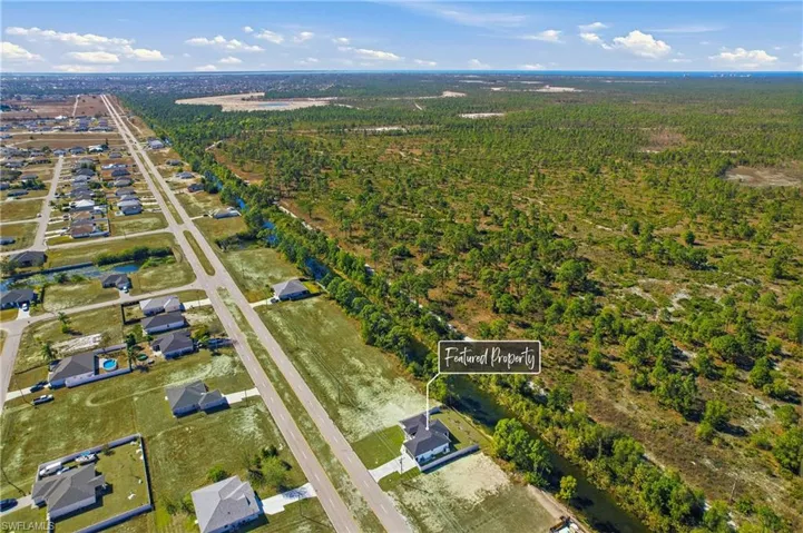 Aerial view of property's location featuring nearby suburban area and a heavily wooded area