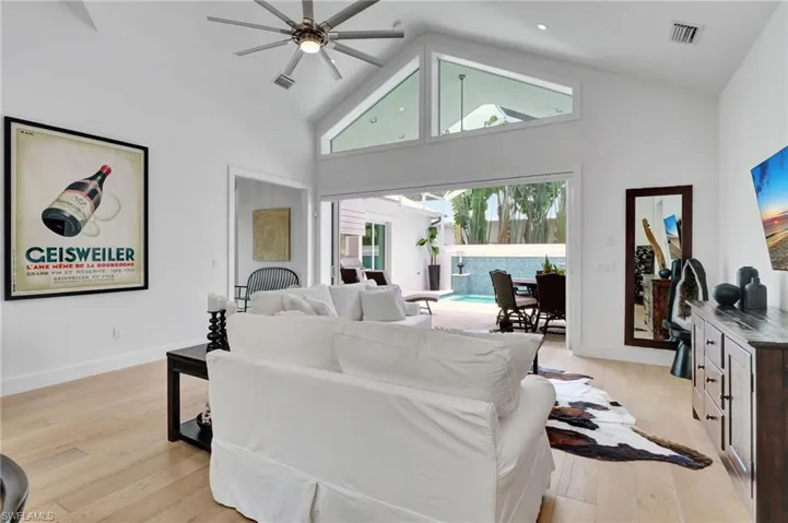Living area with high vaulted ceiling, ceiling fan, and light wood-style floors