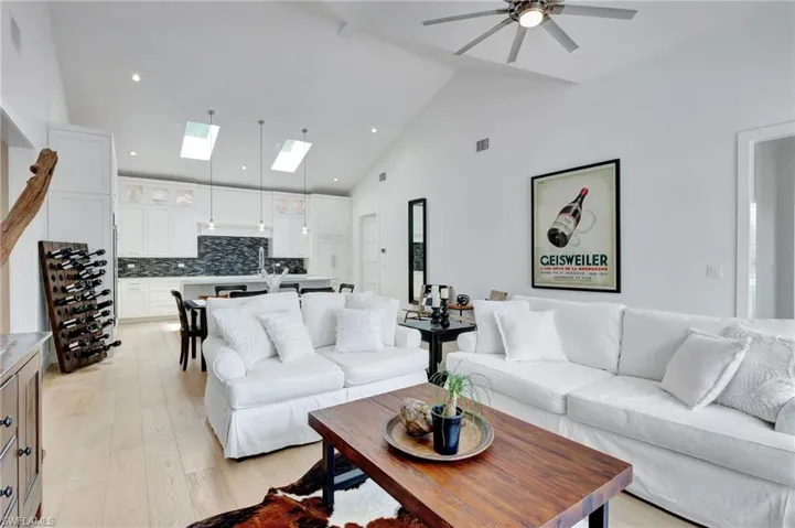 Living area featuring a skylight, a ceiling fan, light wood finished floors, high vaulted ceiling, and recessed lighting