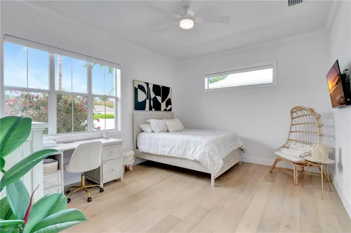 Bedroom with crown molding, light wood-style flooring, an office area, and a ceiling fan