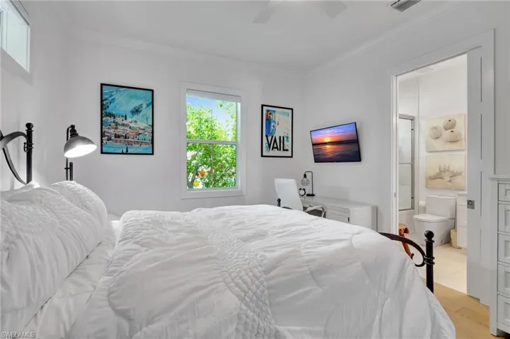 Bedroom with crown molding, light wood-style flooring, ensuite bathroom, and ceiling fan