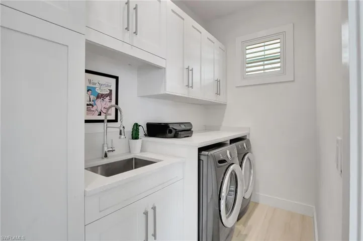 Laundry room with washing machine and dryer, cabinet space, and light wood-style flooring