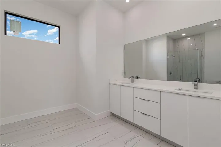 Bathroom with marble look tile flooring, a marble finish shower, recessed lighting, baseboards, and double vanity