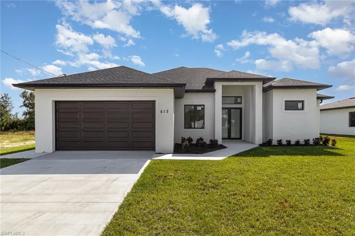 Prairie-style home with stucco siding, driveway, a garage, a front lawn, and roof with shingles