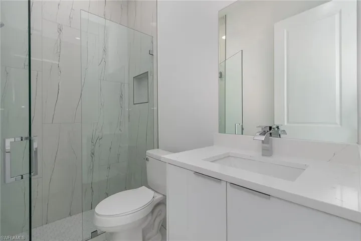 Bathroom featuring toilet, a marble finish shower, and vanity